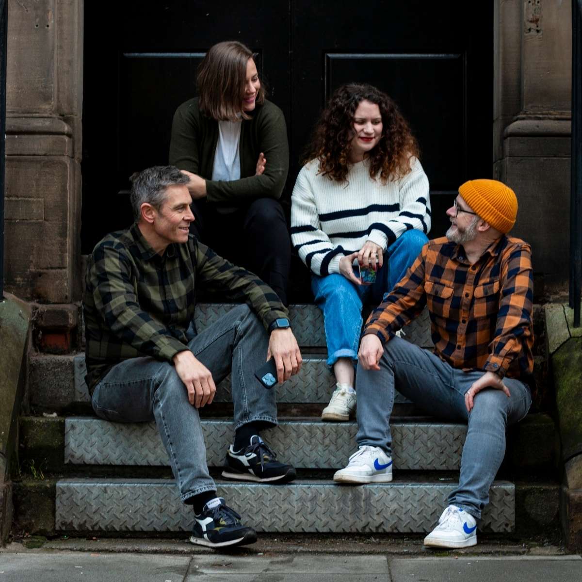 Three Rooms Brand Agency - Team Photos - 4 team members sat chatting on some steps