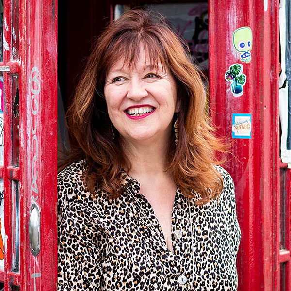 Gill - pictured in a patterned dress, stood in the doorway of a telephone box - captured during a Mini Photo Shoot in London