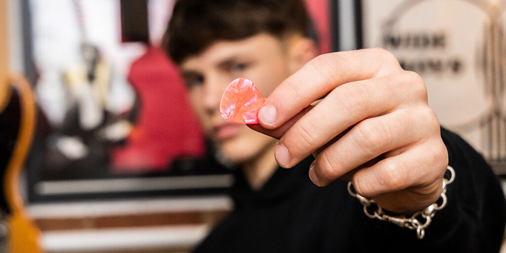 Cool photo ideas for your recording studio - artist holding a guitar pick up to the camera
