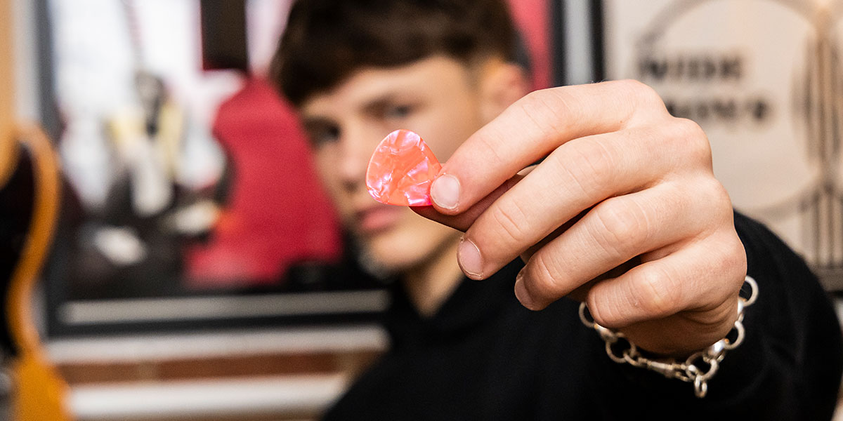 Cool photo ideas for your recording studio - artist holding a guitar pick up to the camera