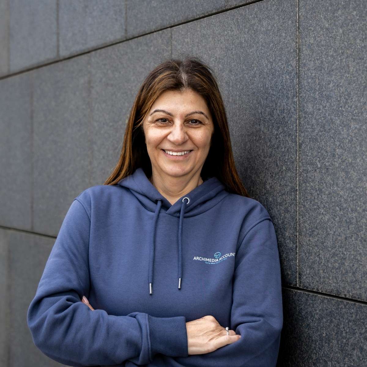 Team Photos - Archimedia Accounts - individual headshot in front of a dark grey wall wearing a branded hoodie - Barbara Demetriou (Founder)