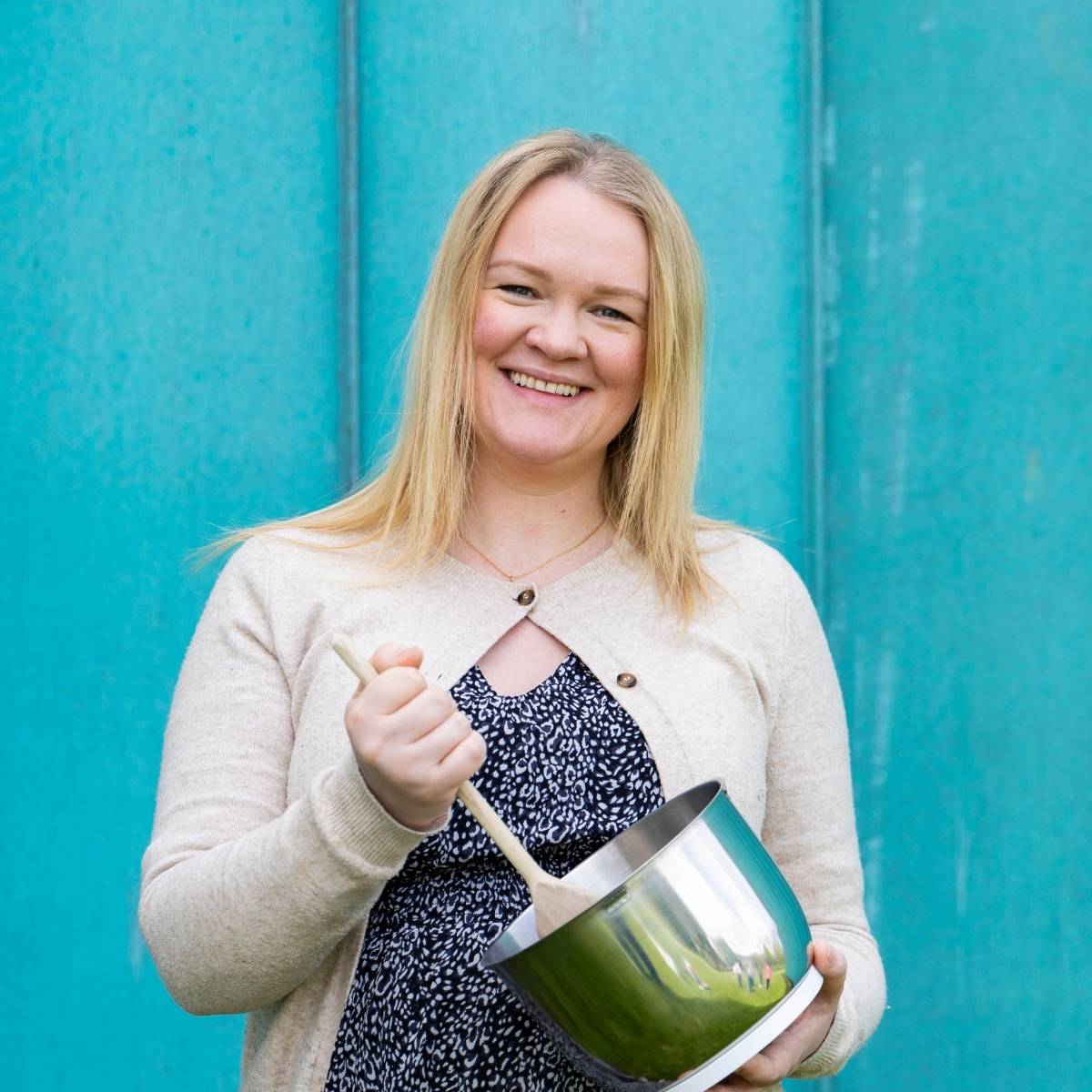 Team Photos - Archimedia Accounts - individual headshot in front of a bright blue wall holding a mixing bowl and a spoon