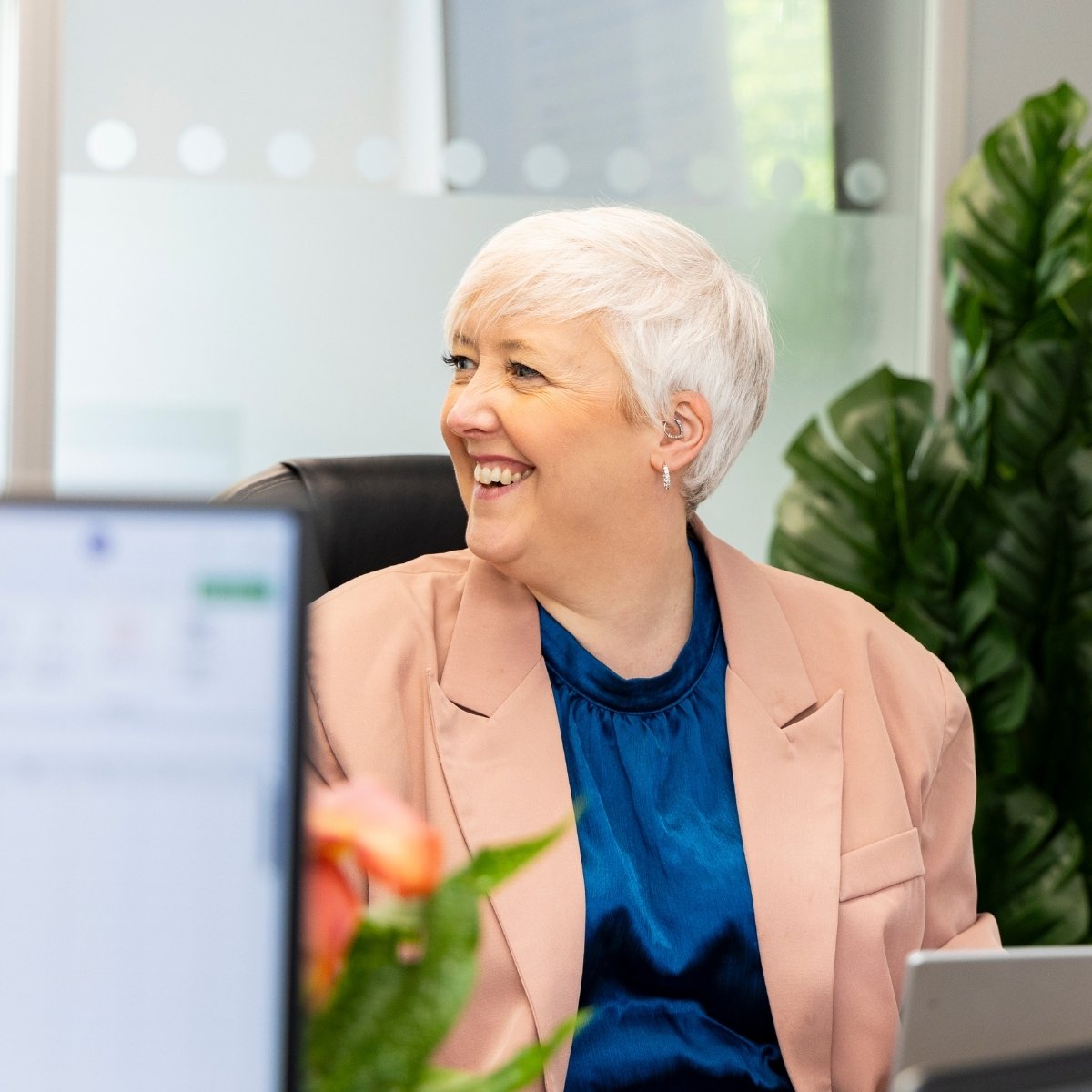 Team Photos - Archimedia Accounts - photo of a team member sat at her desk smiling with a team mate who is out of shot
