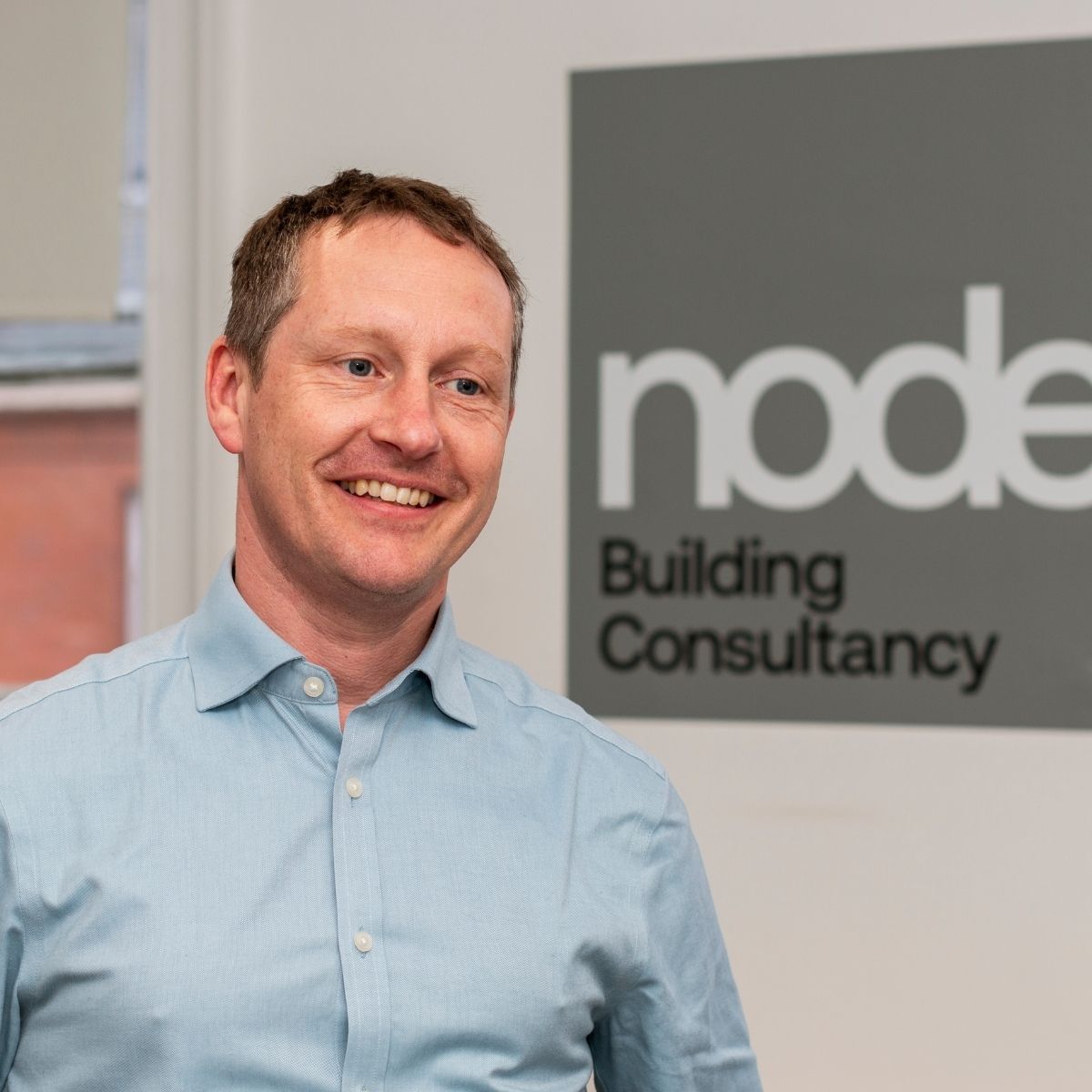Team Photos with Node Building Consultancy, Nottingham - headshot in front of a branded sign