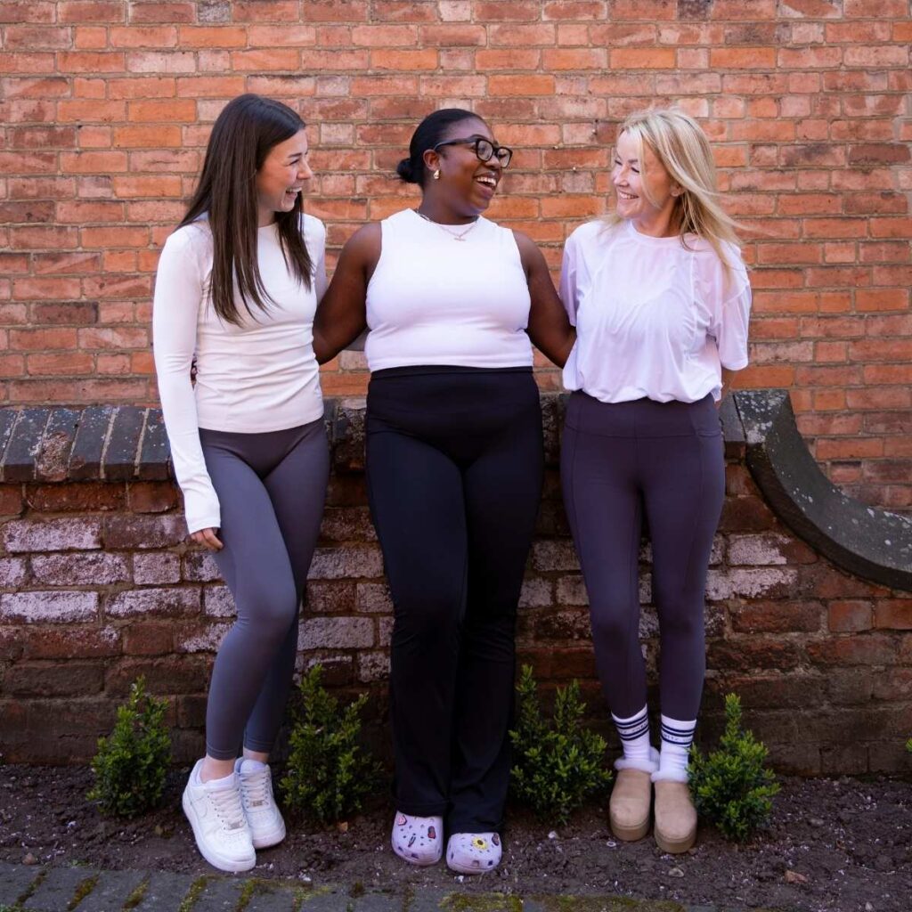 Team Photo - a team of three reformer pilates instructors stood in front of a brick wall