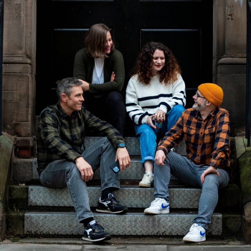 Team Photo - a team of four sat on steps chatting